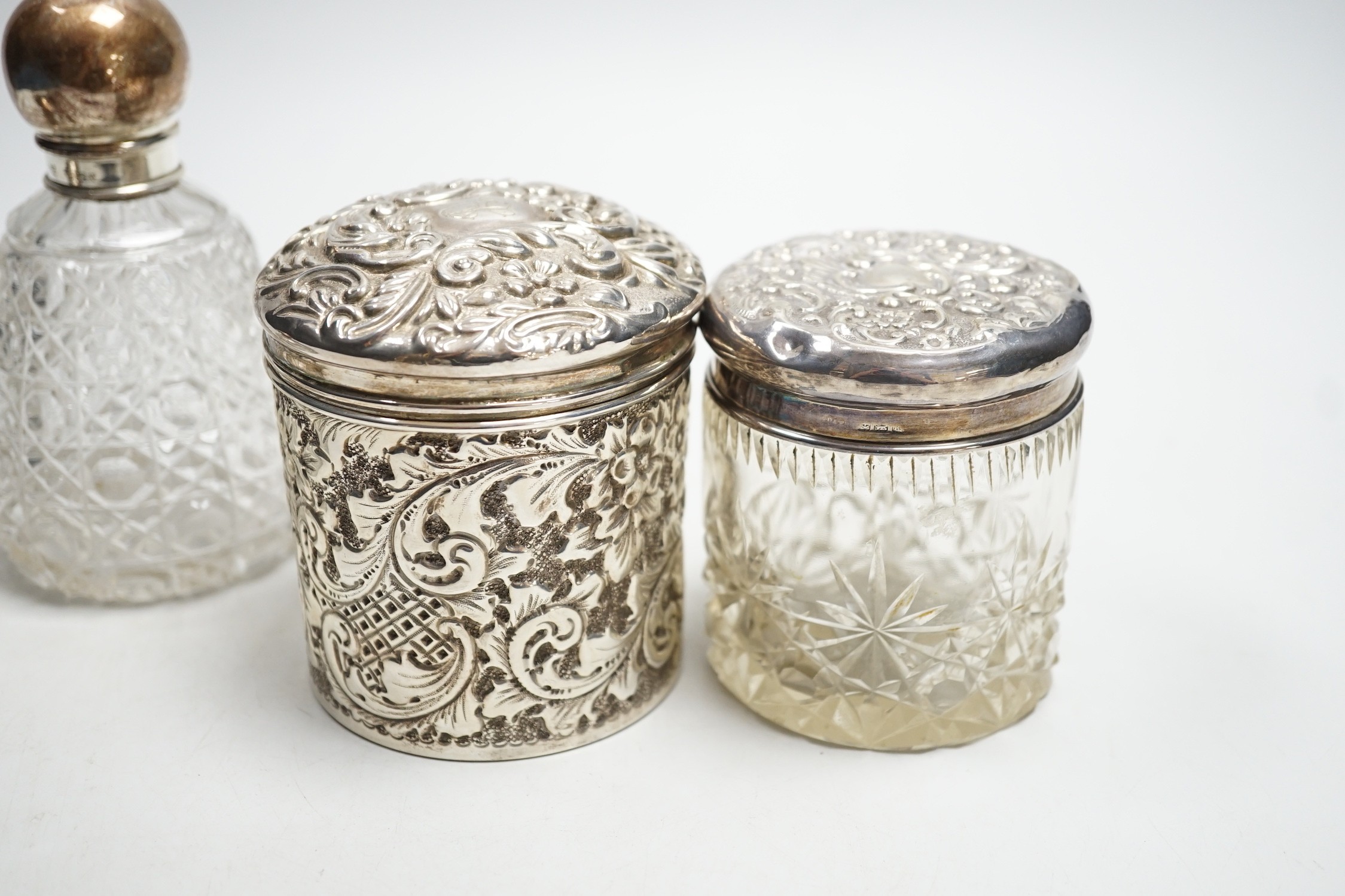 Two repousse silver lidded toilet jars, including glass, largest, 95mm and two silver mounted glass scent bottles.